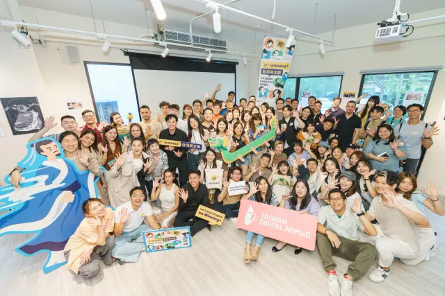 台灣英文週主活動的大合照，滿場參加者在明亮的室內擠進鏡頭，前方有 Taiwan Digital Nomad 的牌子
