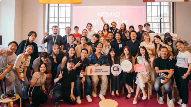Nomad Invasion 活動的大合照，眾人坐在前排、後排站著，手持 Taiwan Digital Nomad 的牌子