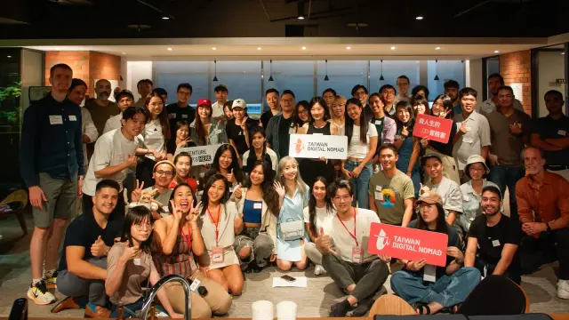 社交聚會的大合照，參加者擠在一起，有人舉著 Taiwan Digital Nomad 的牌子
